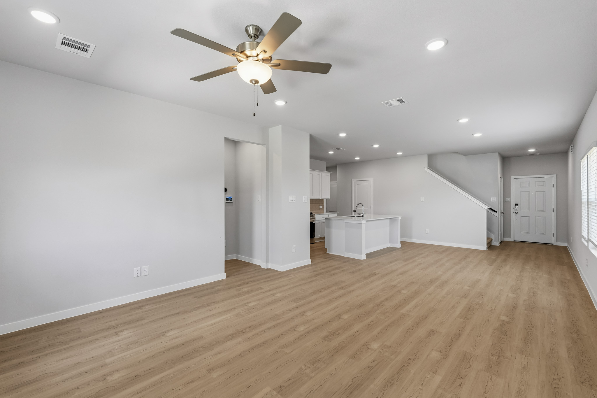 A room with a ceiling fan and a wood floor.