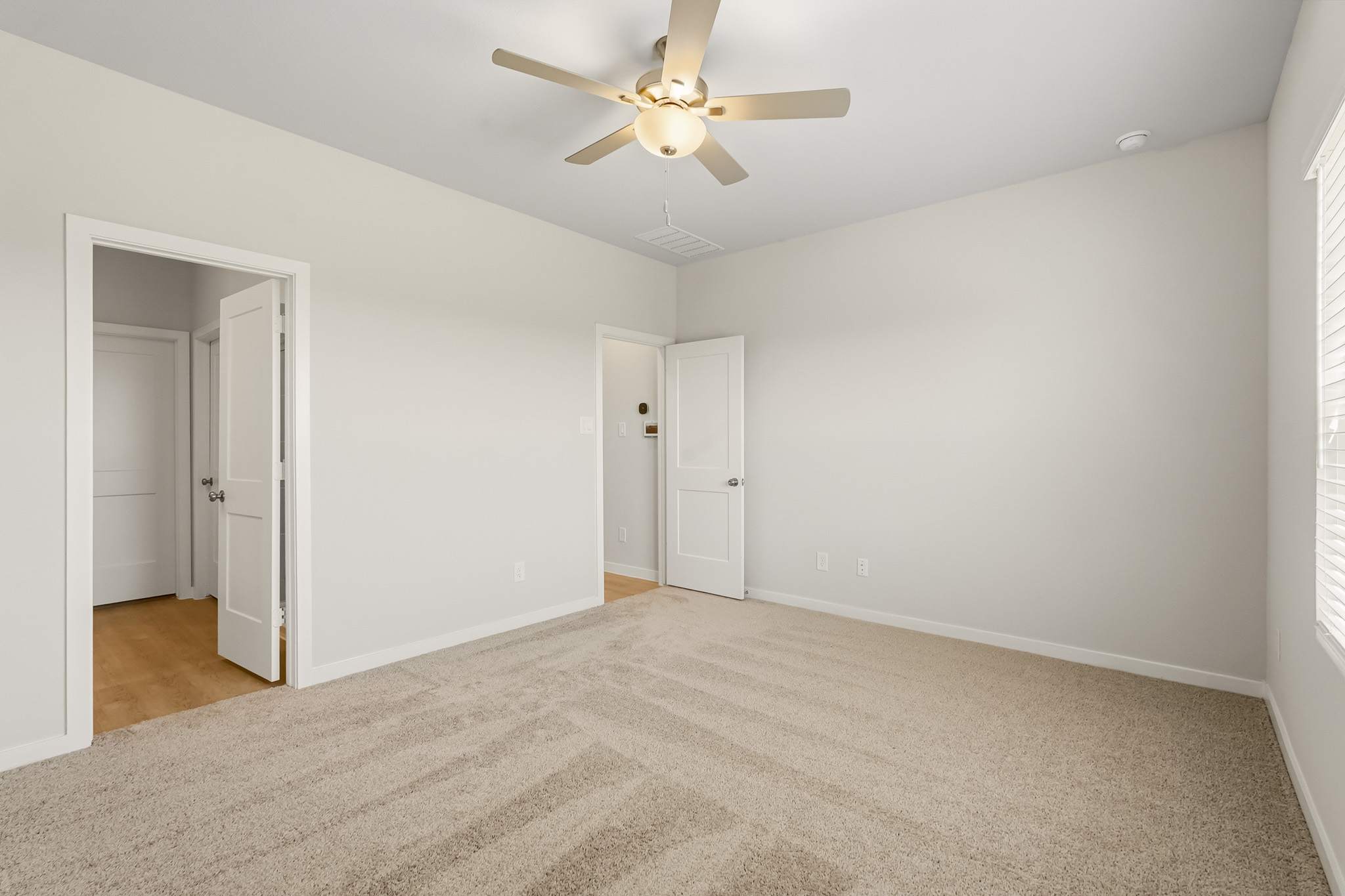 A room with a ceiling fan and white doors.
