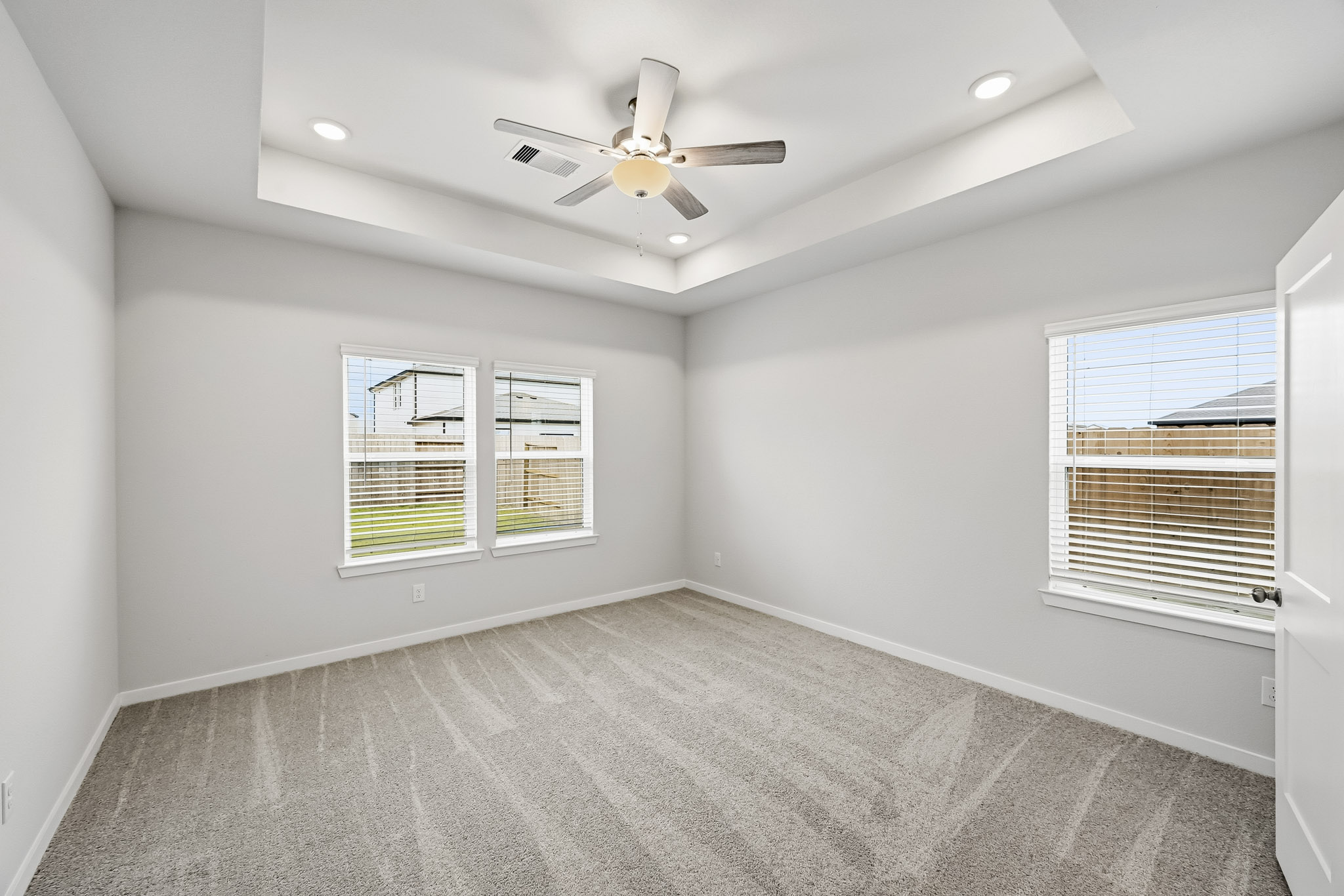 A room with a ceiling fan and windows.