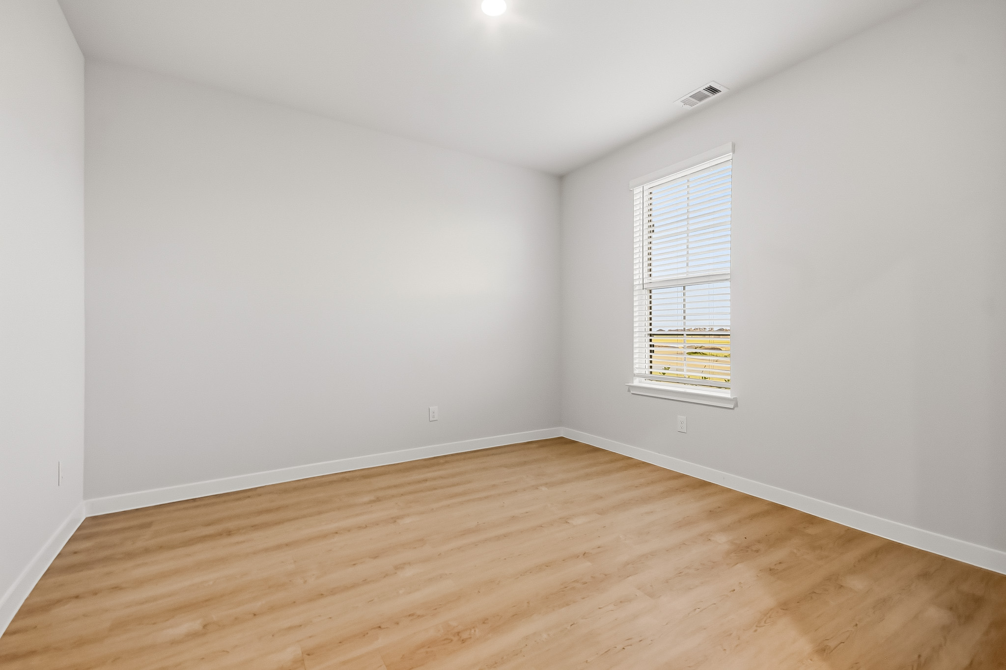 A room with a wood floor and a window.