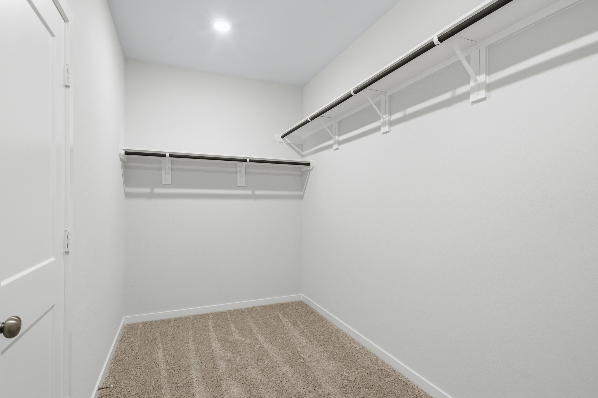 A white room with a carpet and a metal railing.