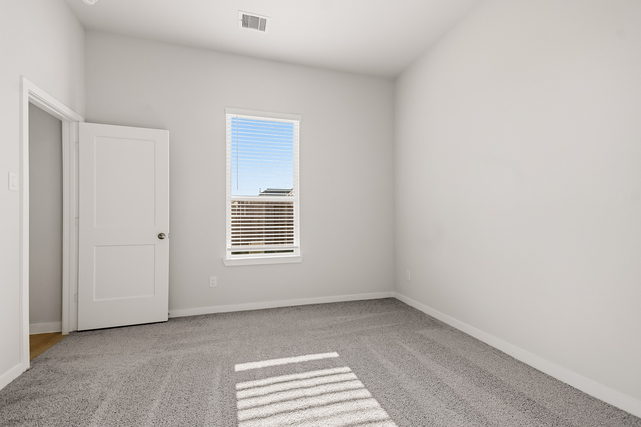 A room with a window and a rug.