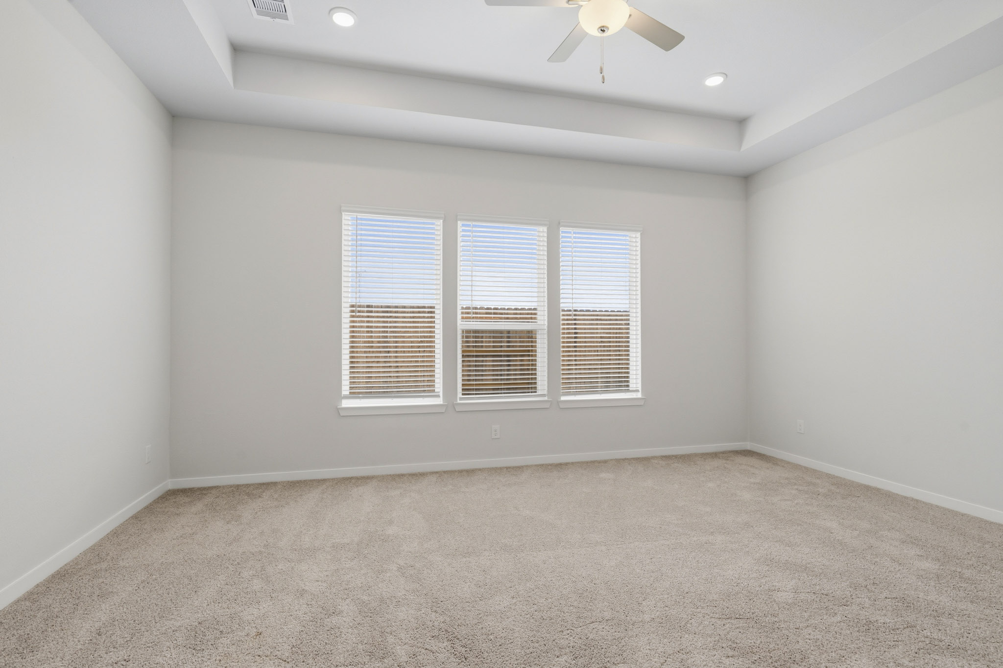A room with a ceiling fan and a carpet.