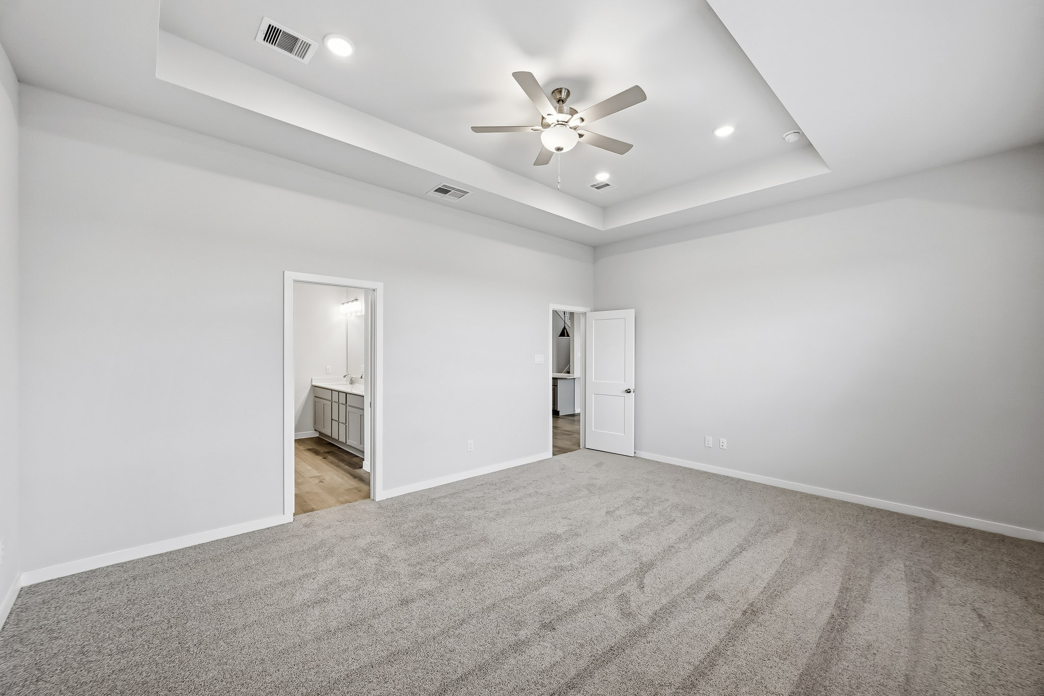 A room with a ceiling fan and a carpet.
