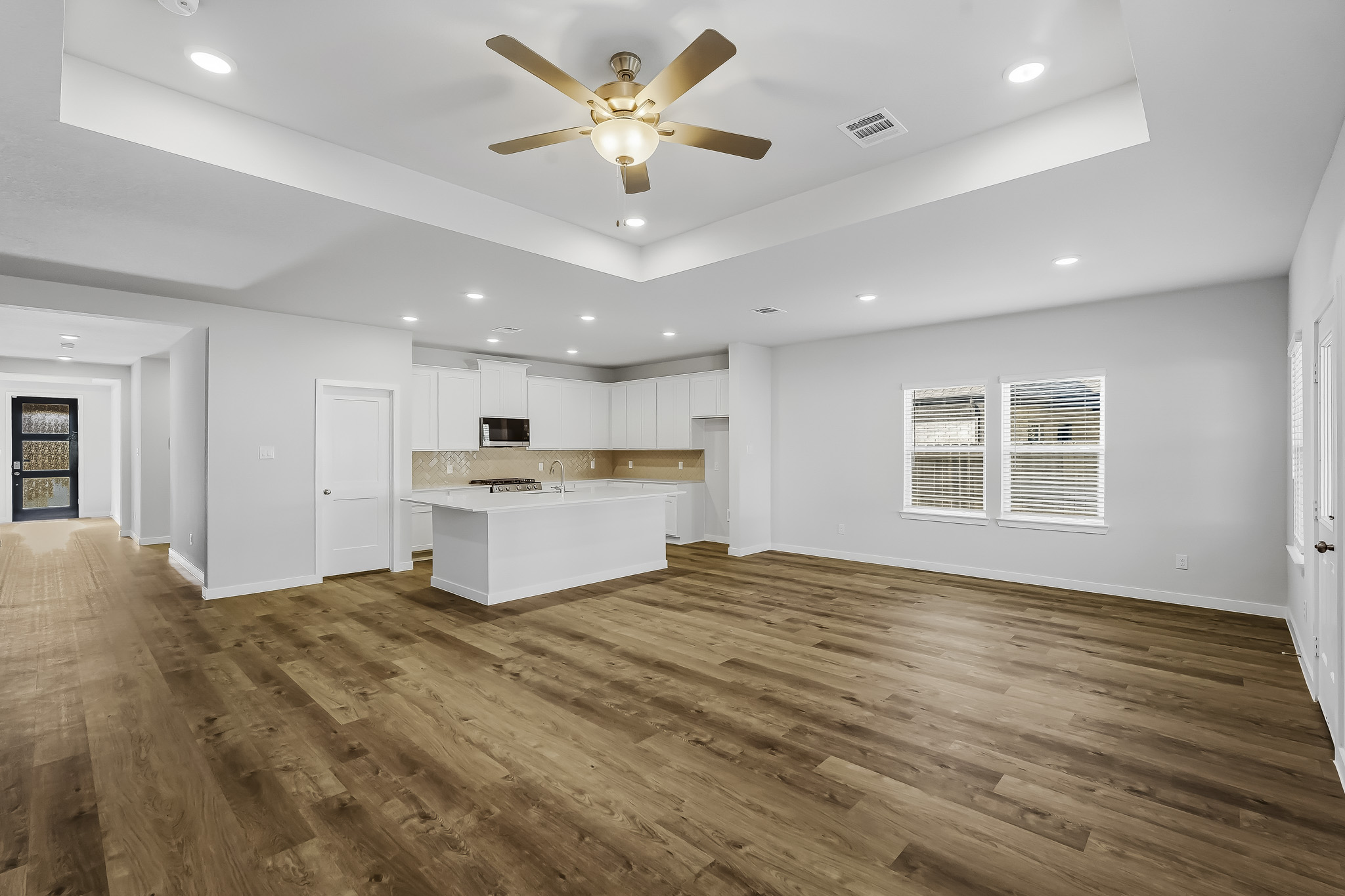 A large empty room with a wood floor and a ceiling fan.