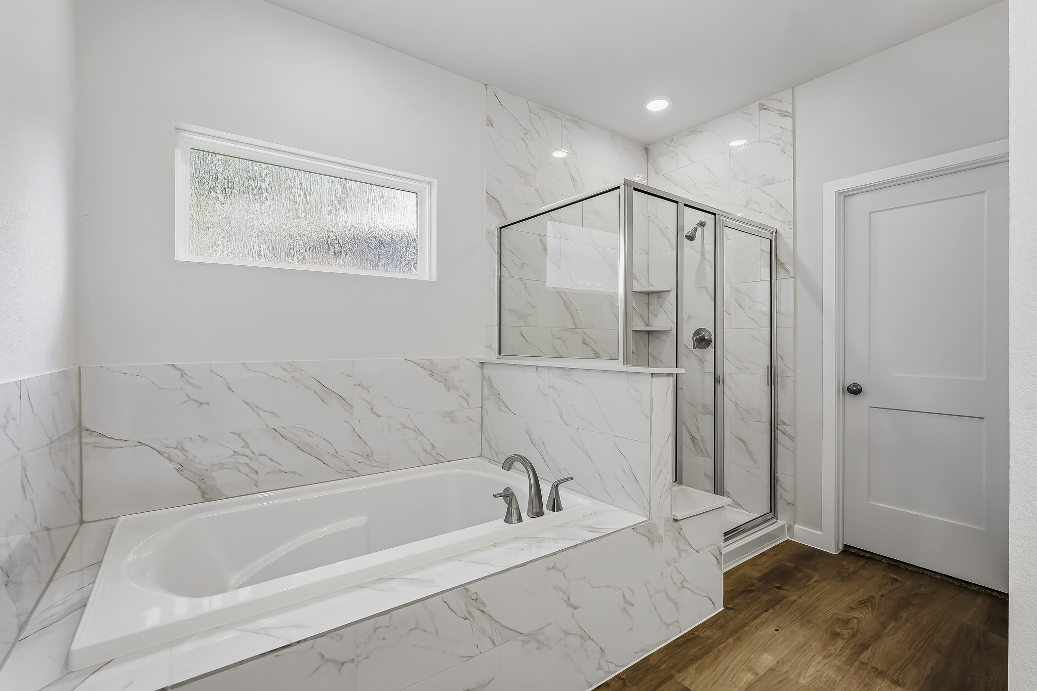 A bathroom with a tub and a glass door.