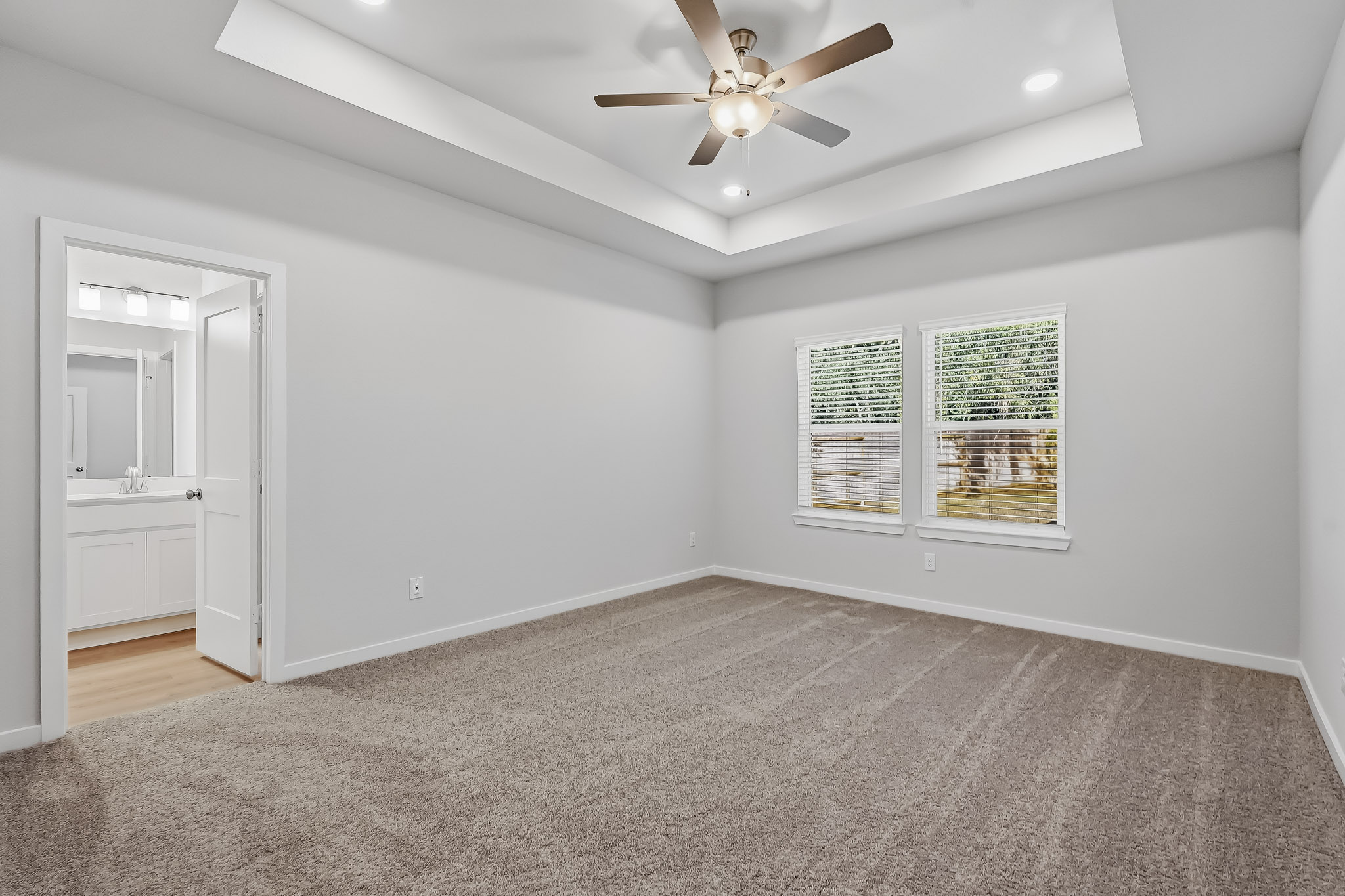 A room with a ceiling fan and a carpet.