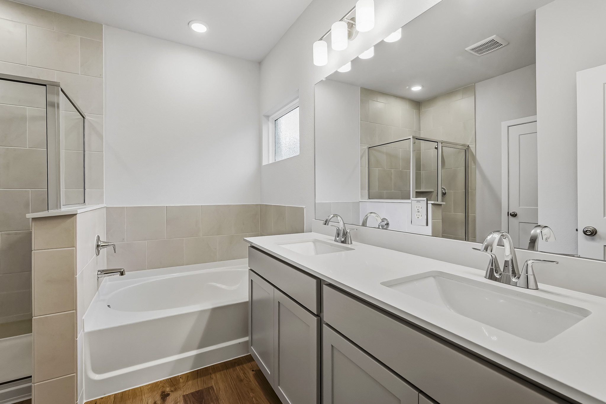 A bathroom with a tub sink and mirror.