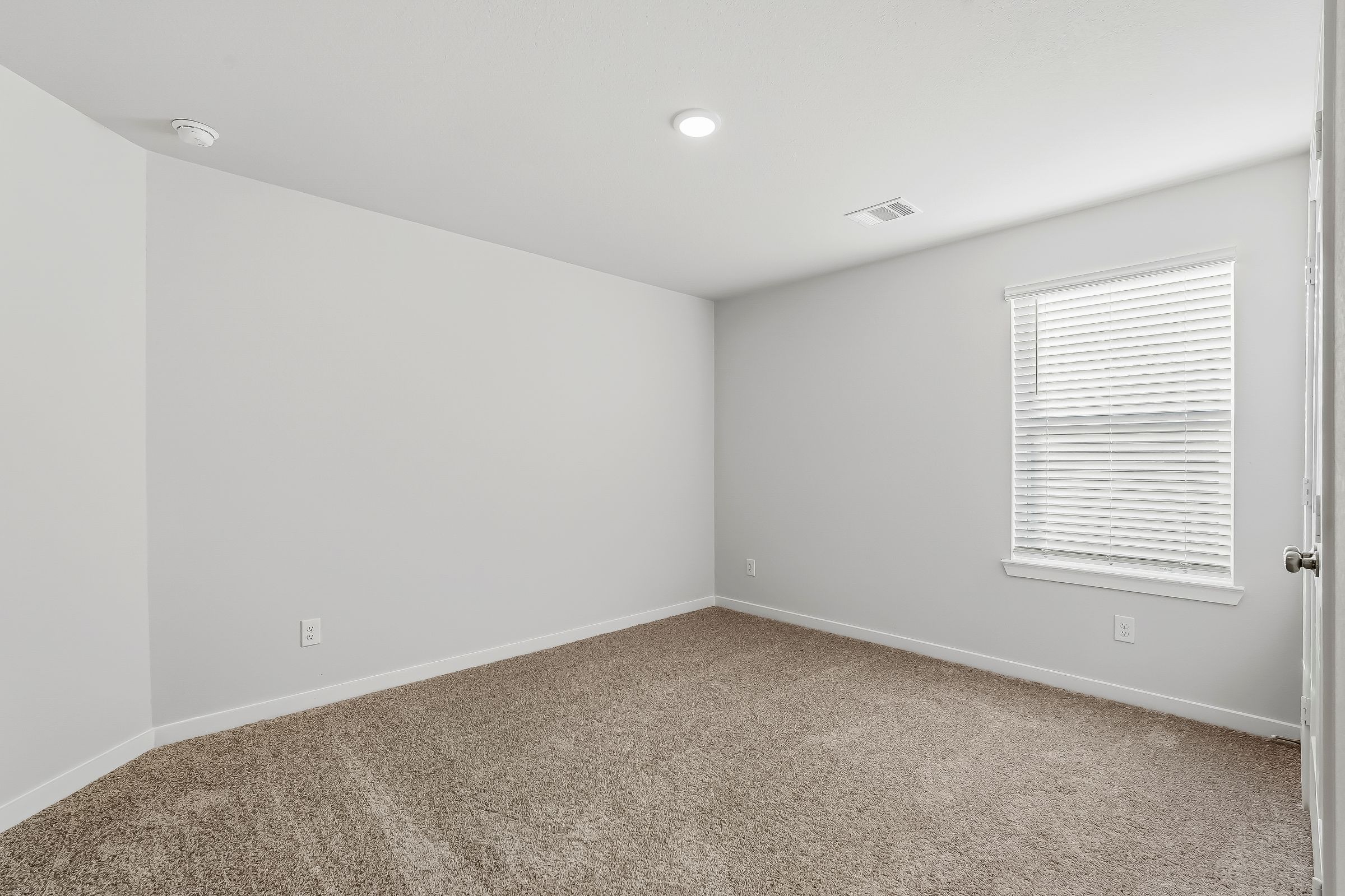 A room with a carpet and a window.