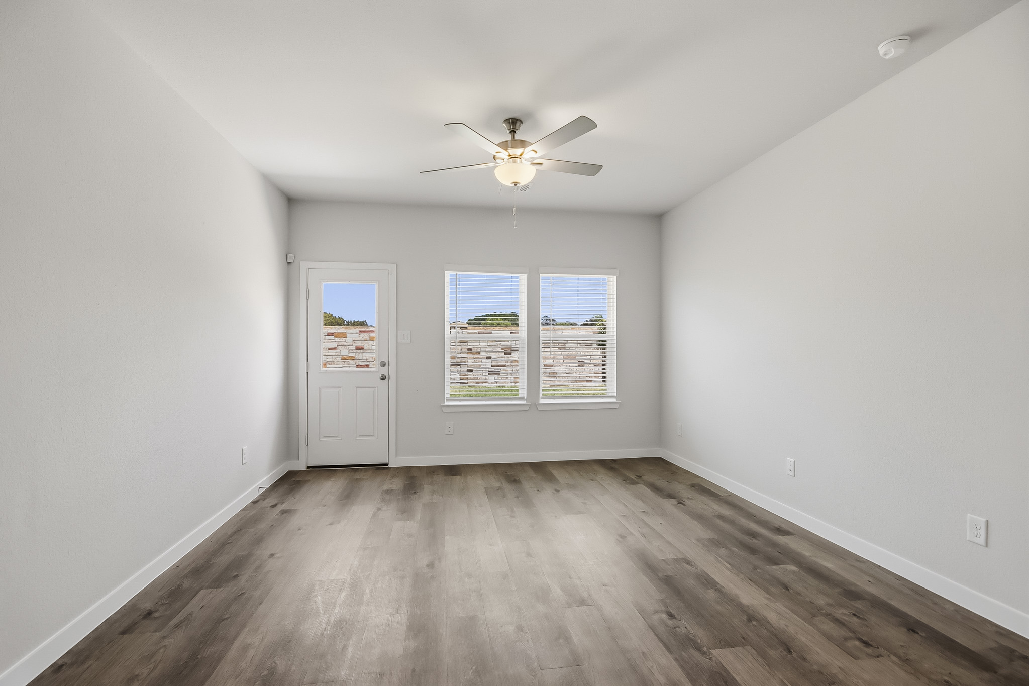 A room with a ceiling fan and a wood floor.