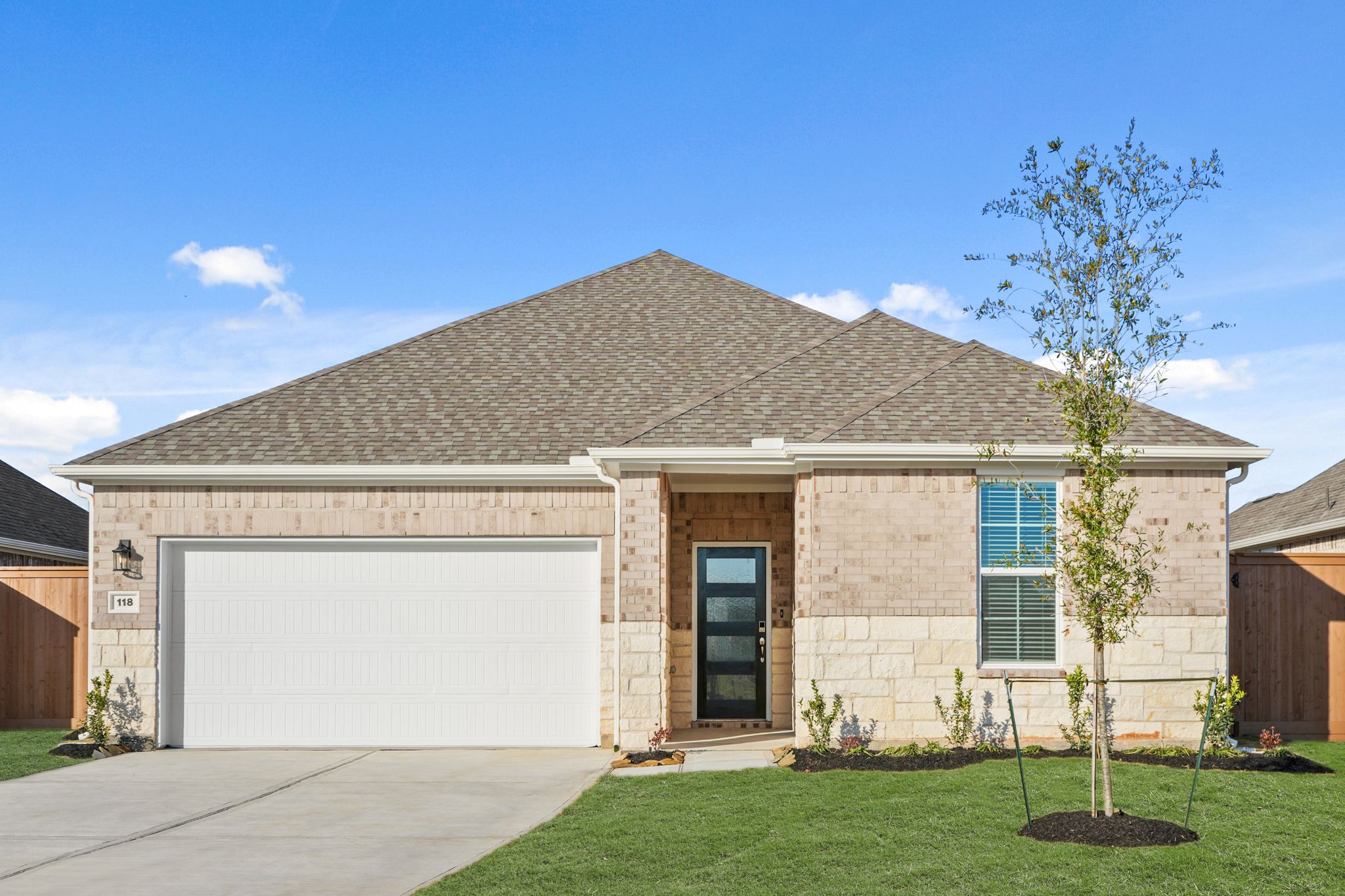 A house with a garage and a tree in the front.