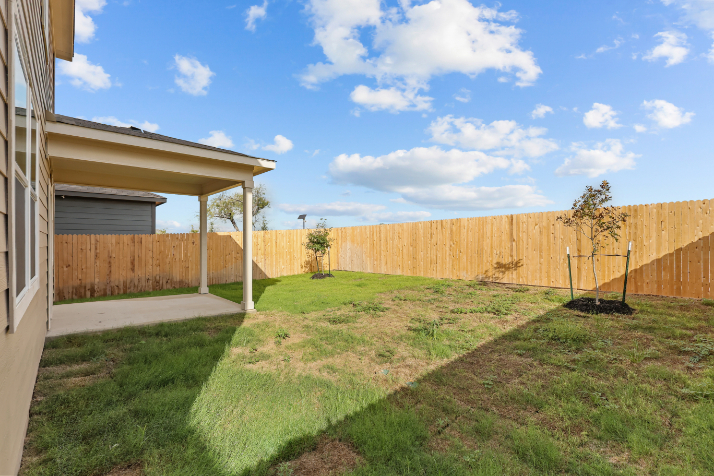 A fenced in yard with a tree and a house.