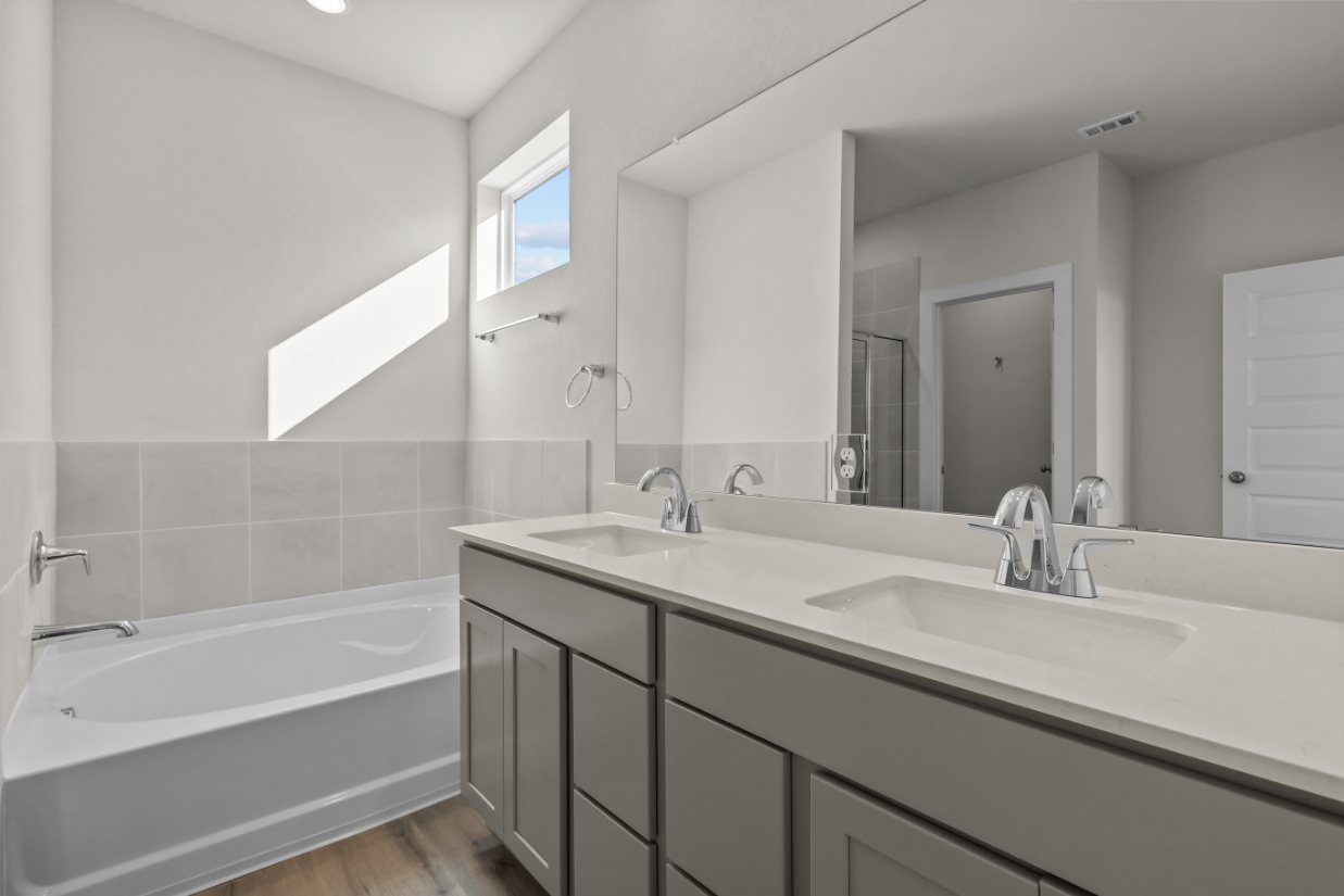 A bathroom with a tub sink and mirror.