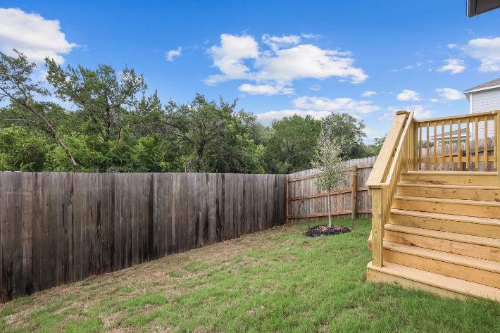 A fenced in yard with trees and a wood fence.