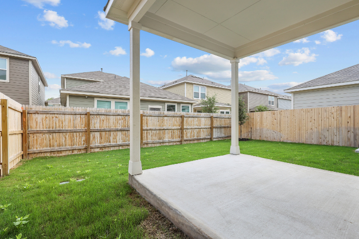 A backyard with a fence and a covered patio.