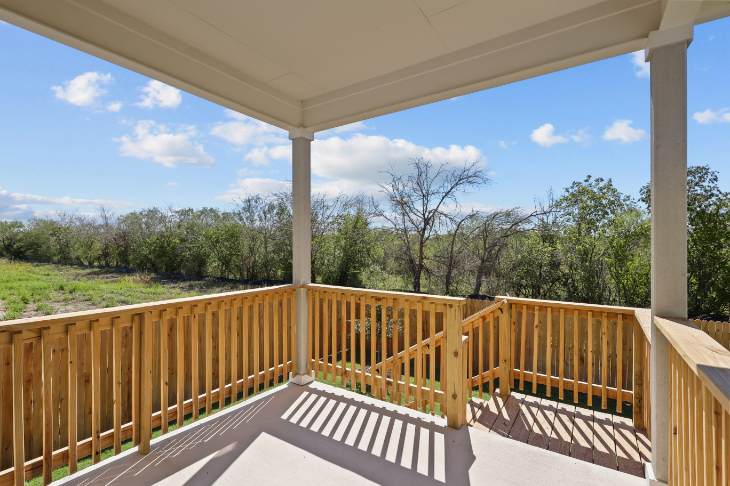 A deck with a railing and trees in the background.