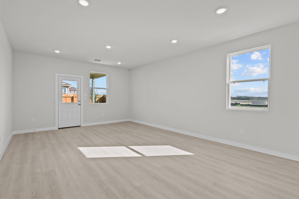 A room with a wood floor and a window with a view of the water.