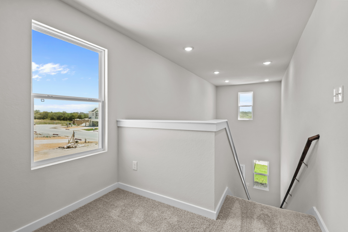 A room with a window and a white wall with a painting on it.