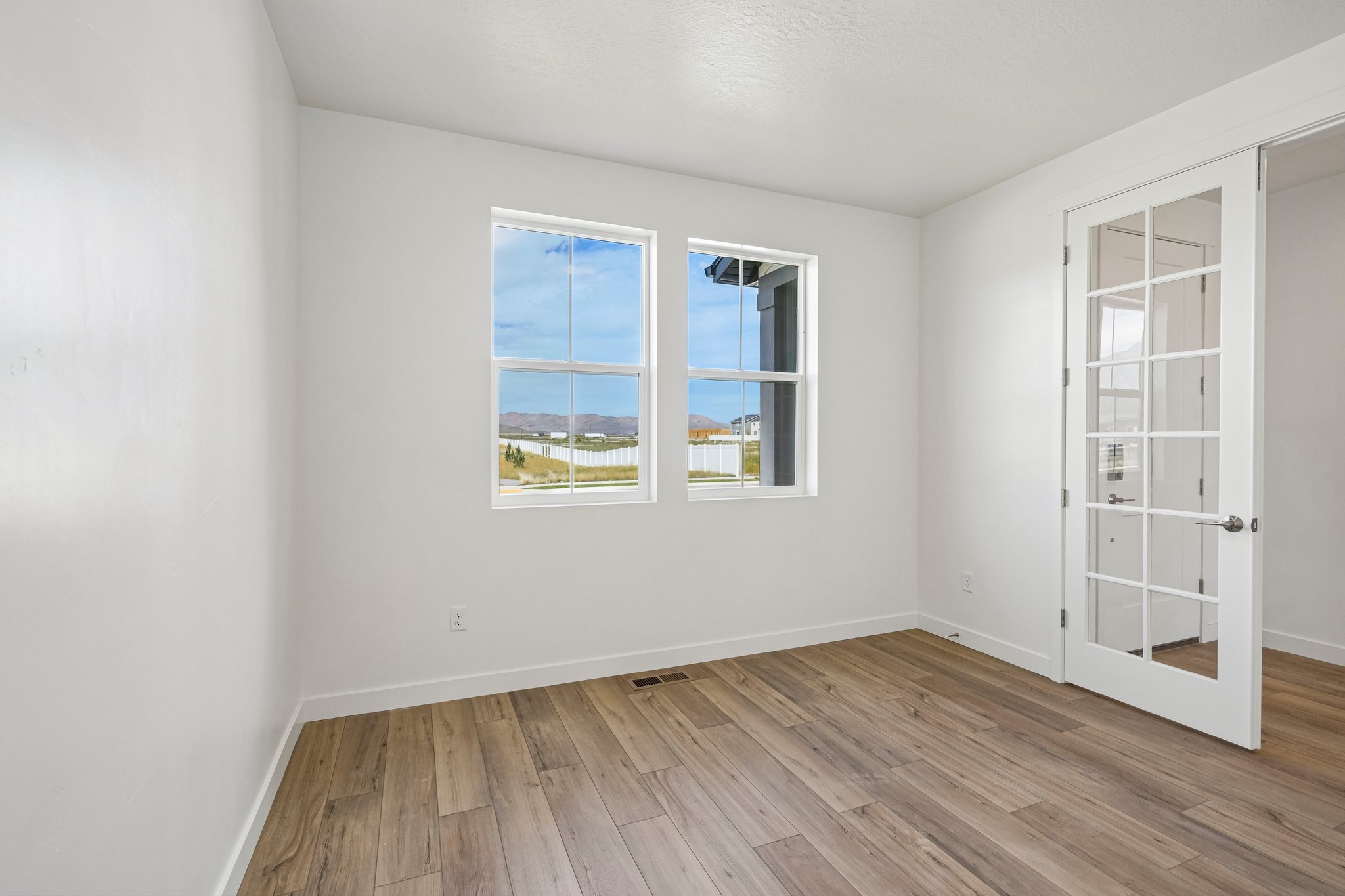 A room with a wood floor and a window with a view of the city.