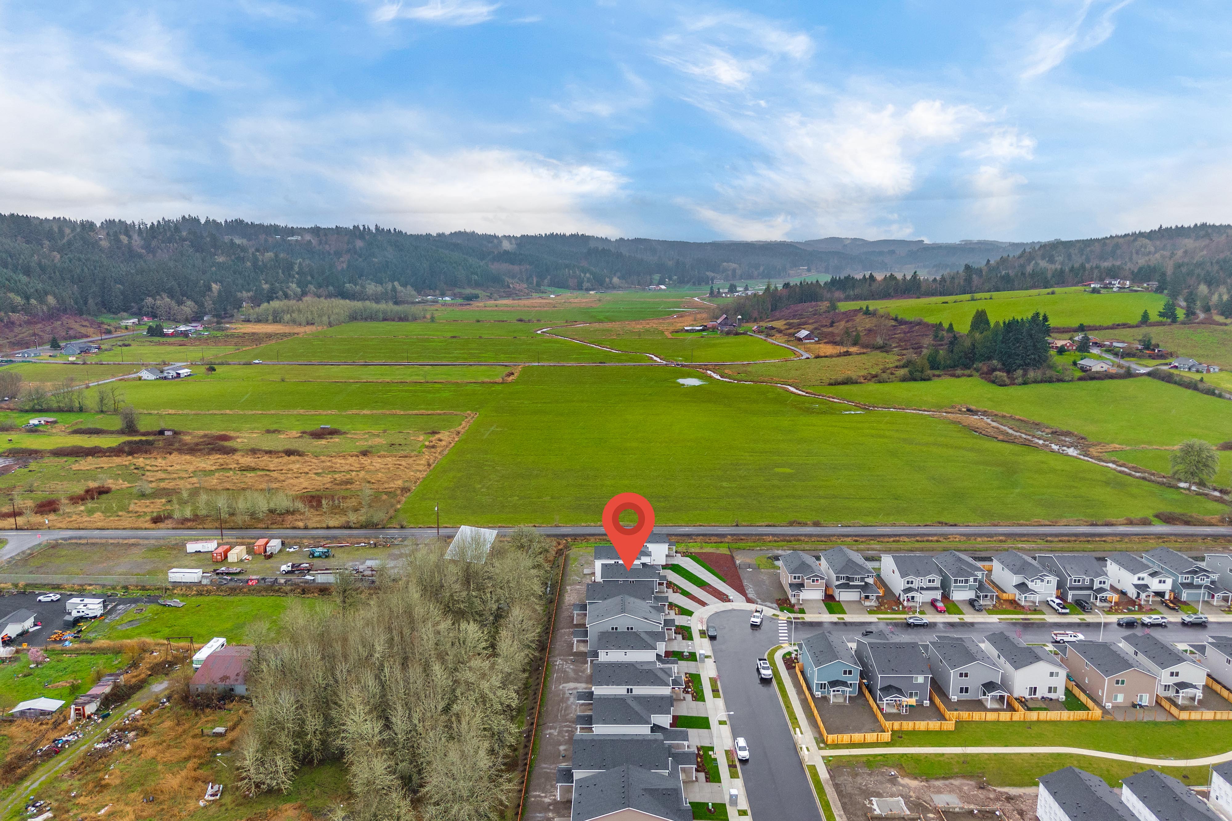 A large green field with buildings and trees.