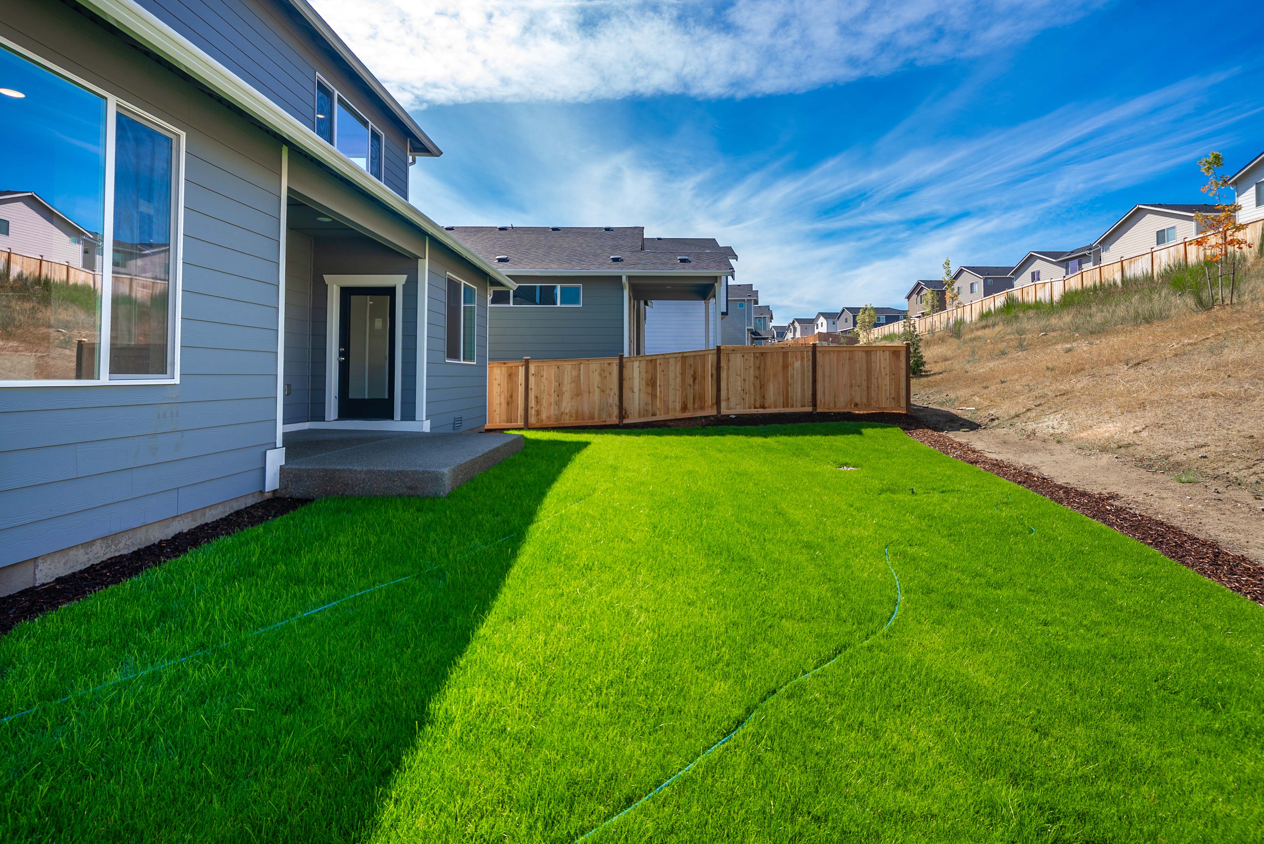 A backyard with a fence and a house.