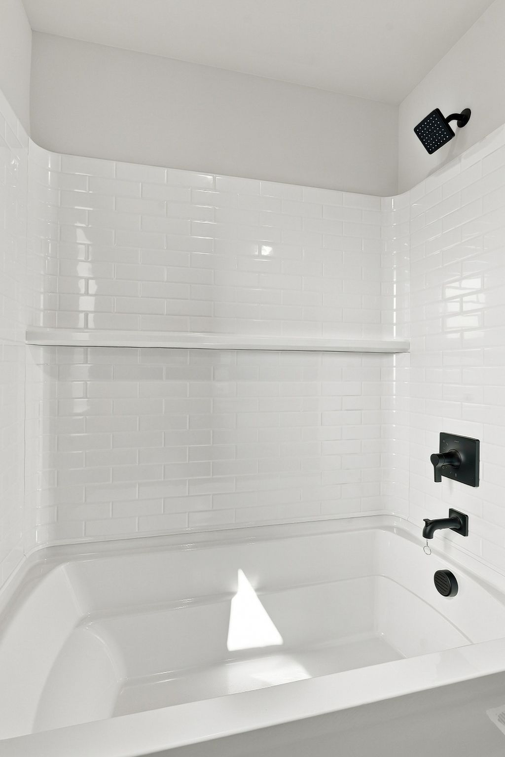 A bathtub with a white tile wall.