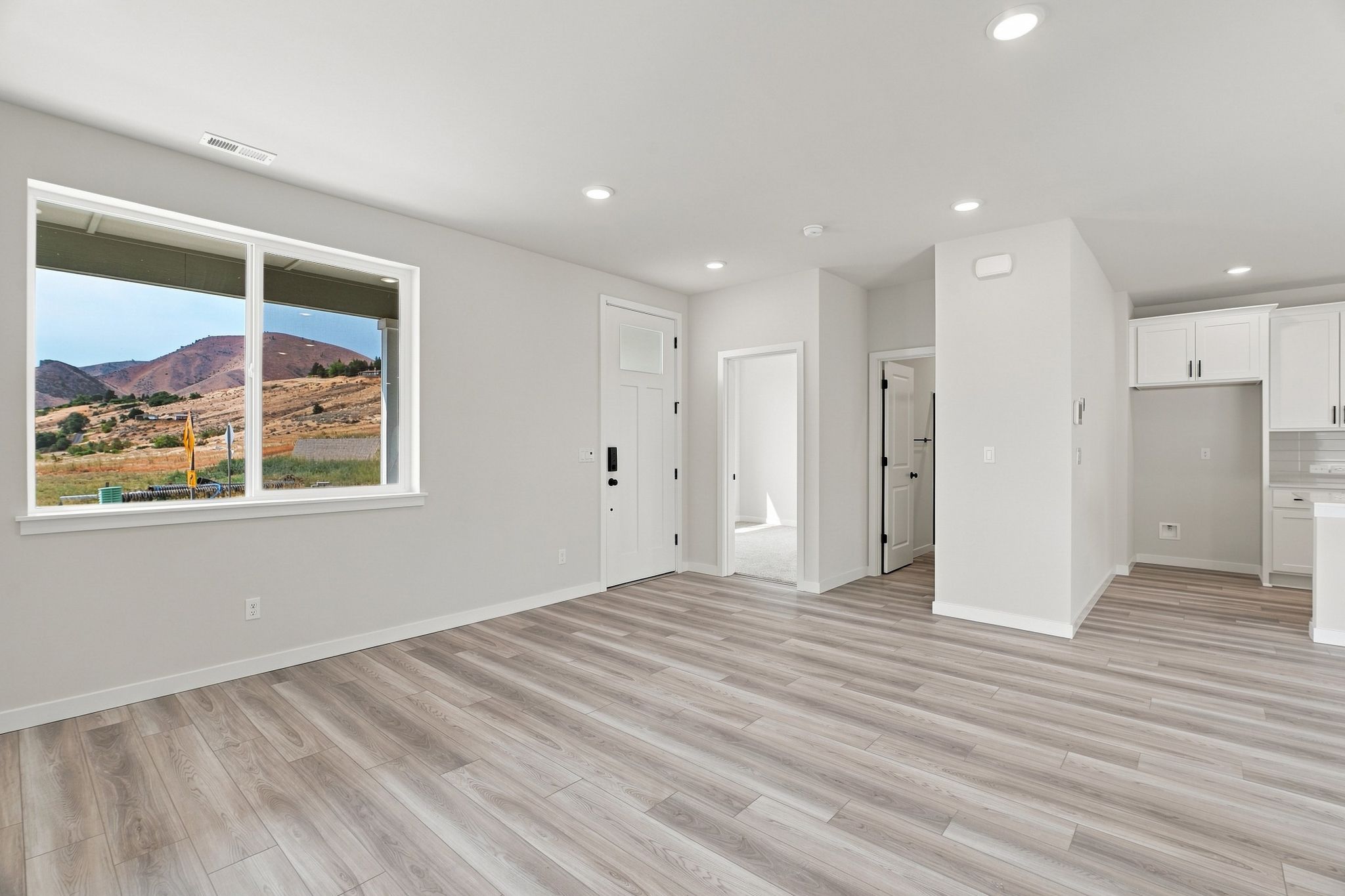 A room with white walls and a wood floor with a large window.