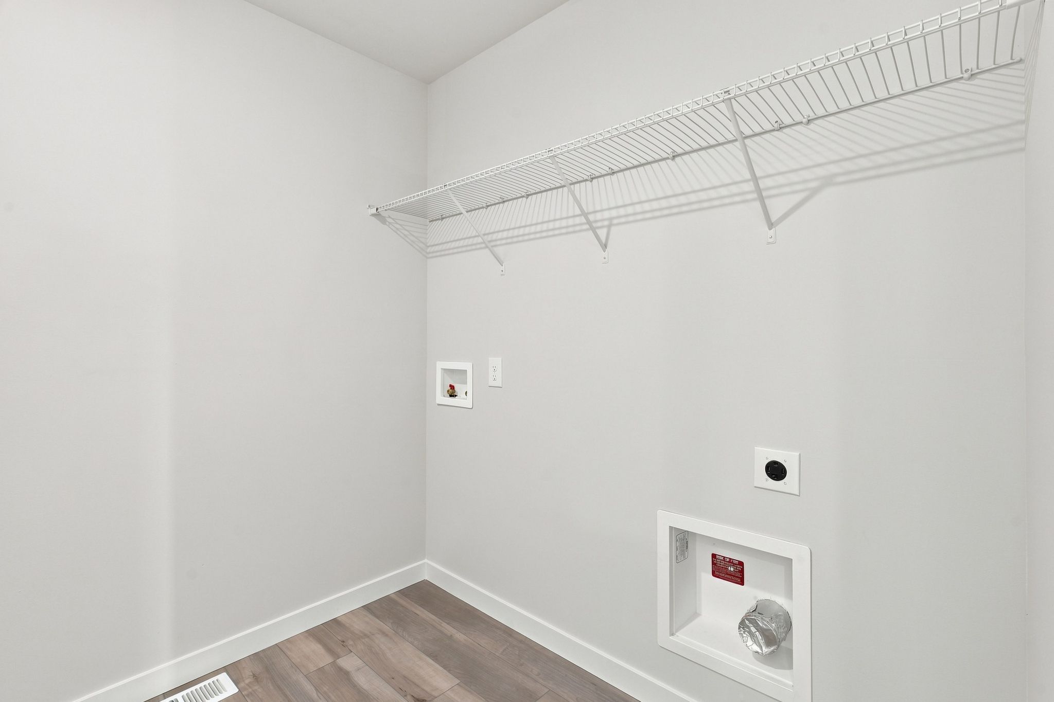A white room with a vent and a wood floor.