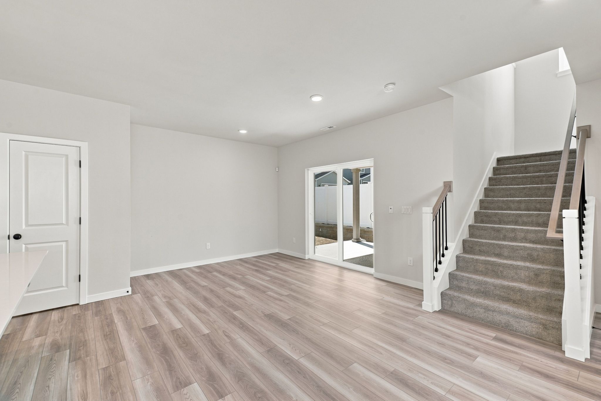 A large empty room with a wood floor and a staircase.