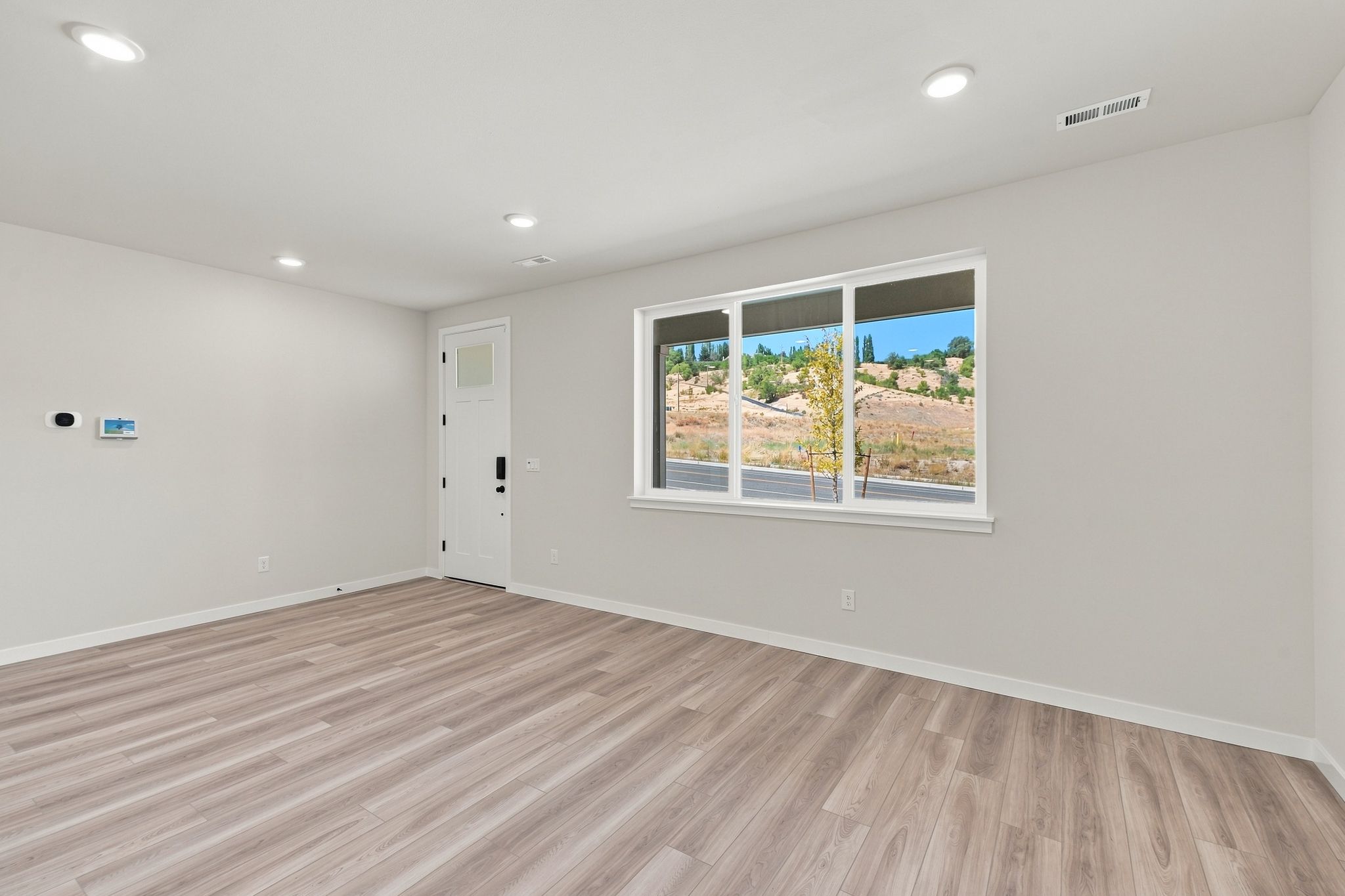 A room with a window and a wood floor.