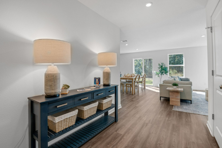 A room with a wood floor and a wood floor with a table and chairs and a lamp.