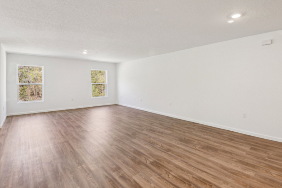 A room with a wood floor and paintings on the wall.
