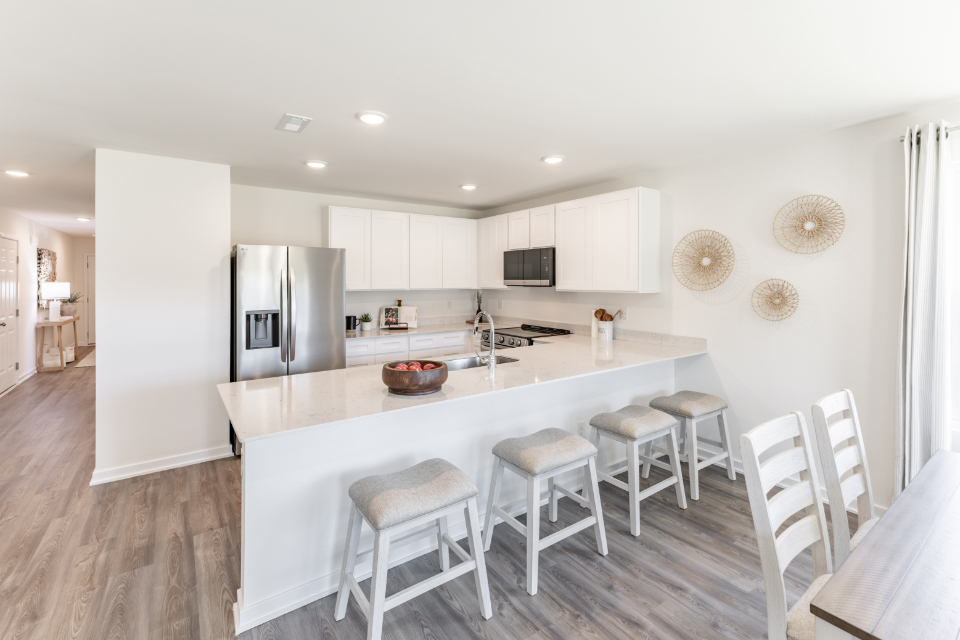 A kitchen with a bar stool and a white refrigerator.
