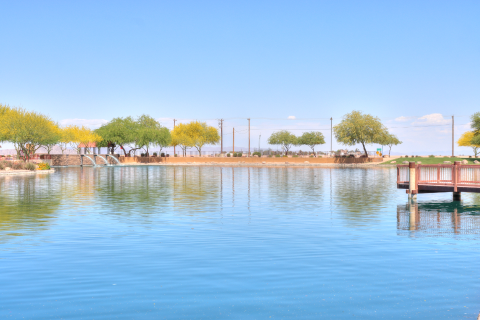 A body of water with trees and a bridge in the background.