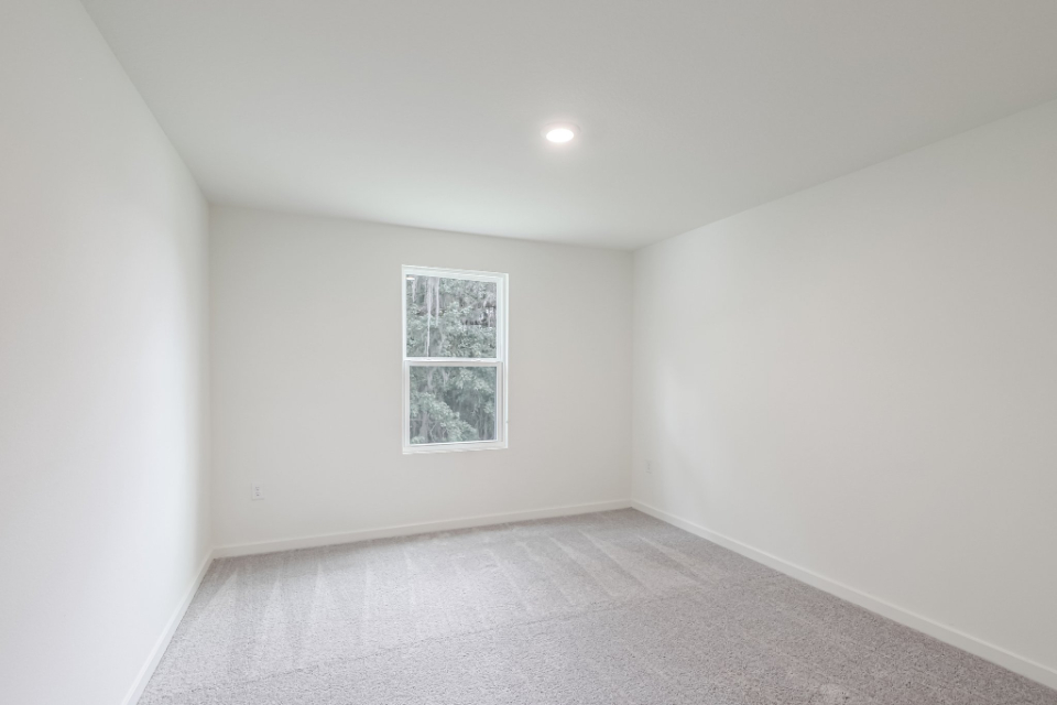 A room with a white carpet and a window.