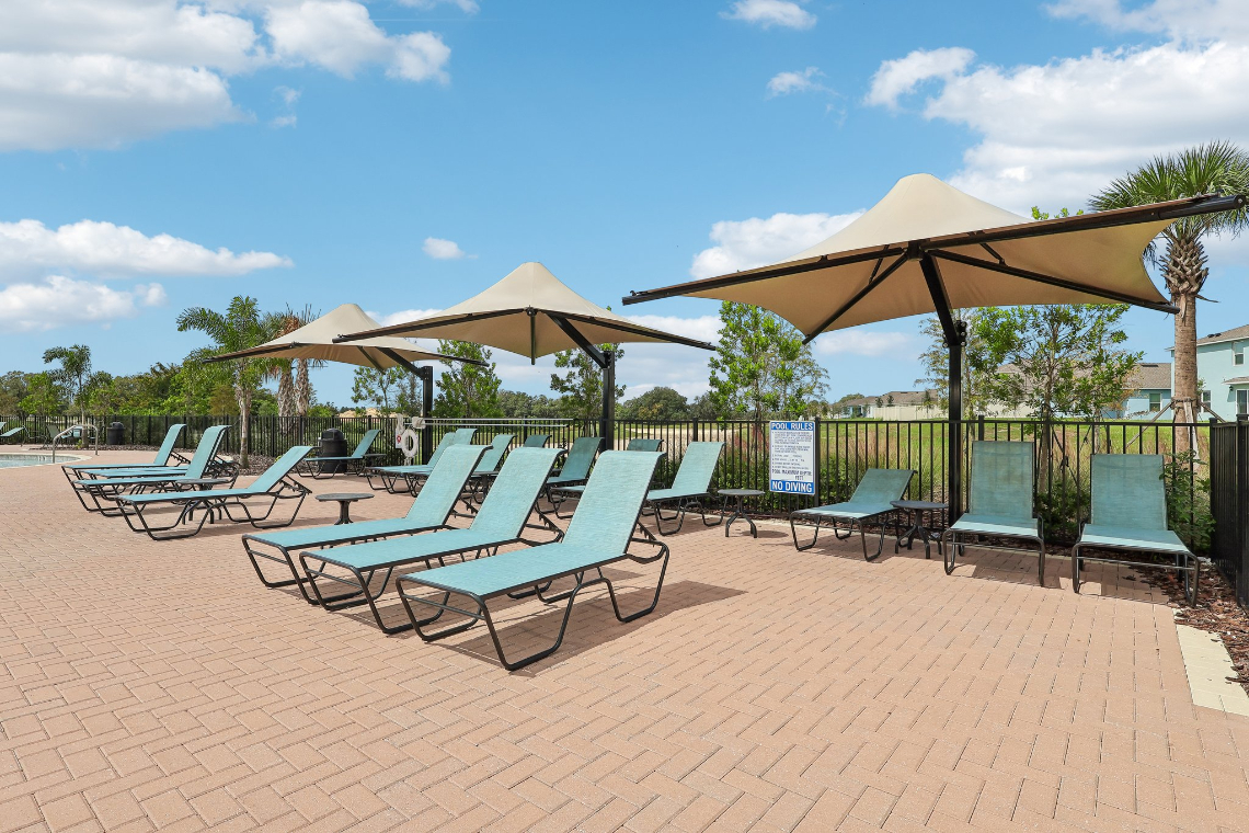 A group of chairs sit under umbrellas on a brick patio.