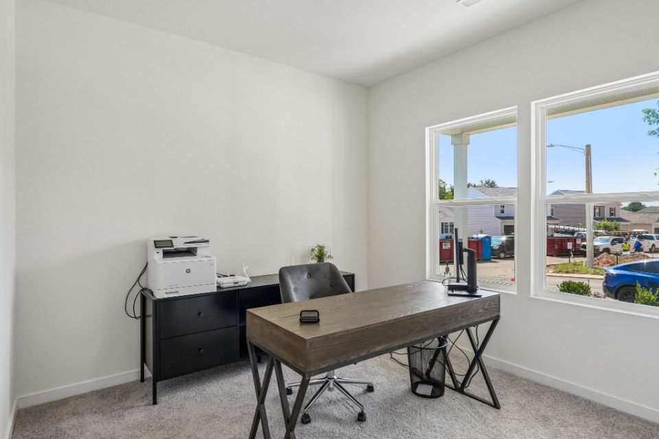 A desk and a chair in a room with a window.