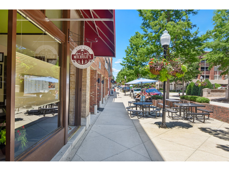 A sidewalk with tables and chairs.