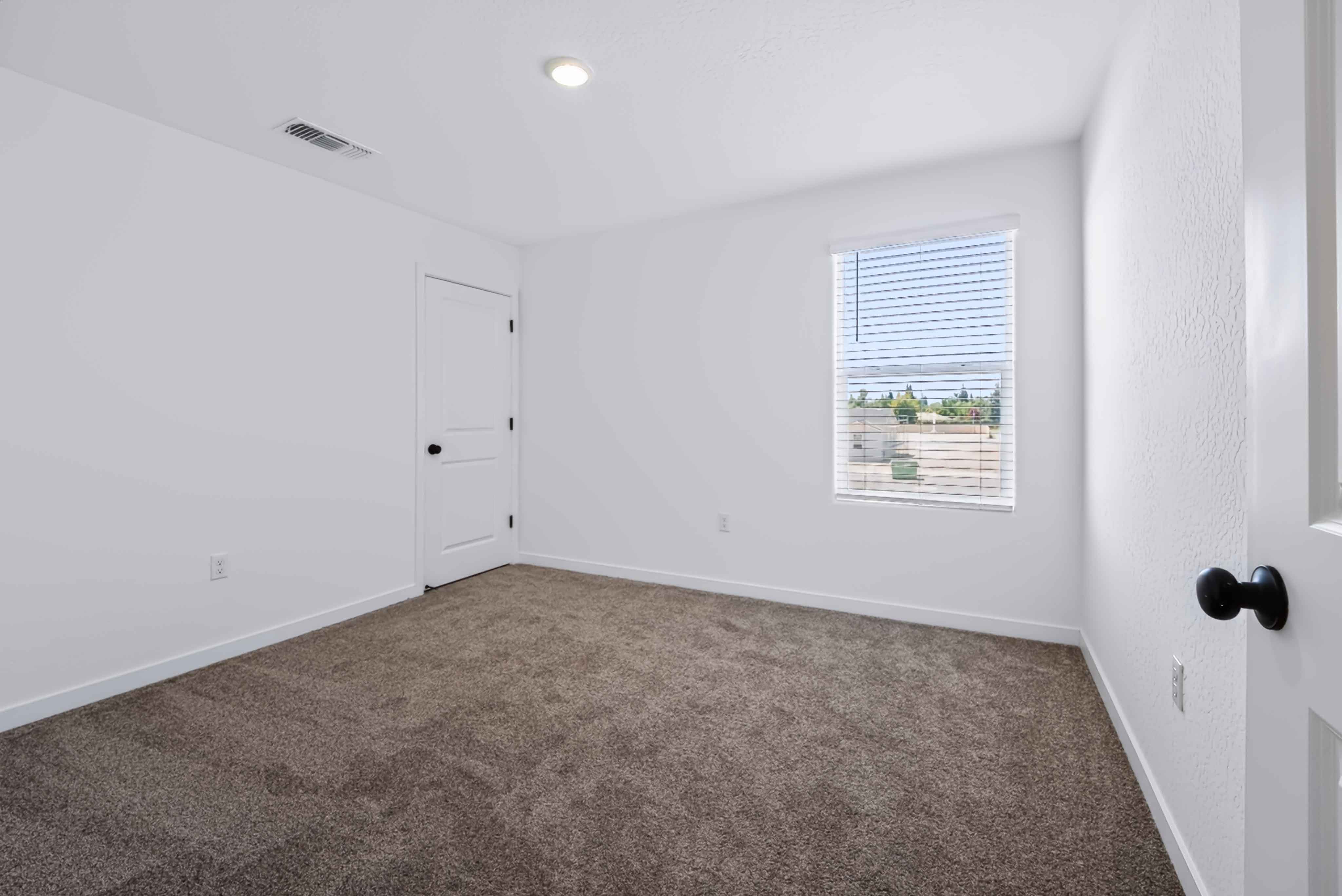A room with white walls and a door with a window.